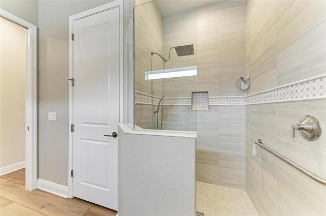 bathroom with hardwood / wood-style flooring and tiled shower