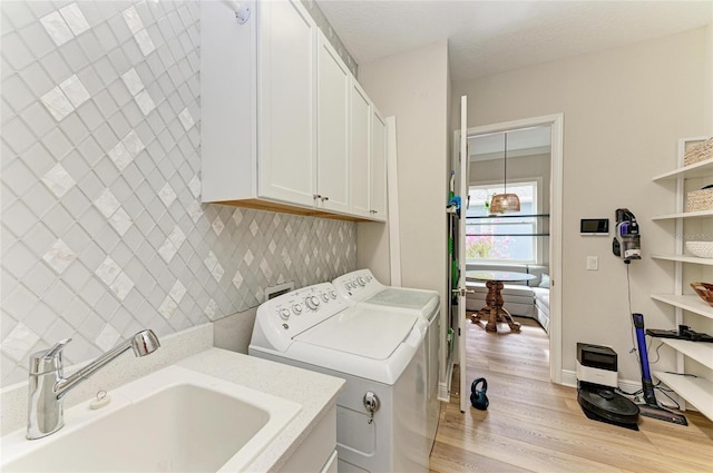 washroom with cabinets, sink, washing machine and dryer, and light hardwood / wood-style flooring