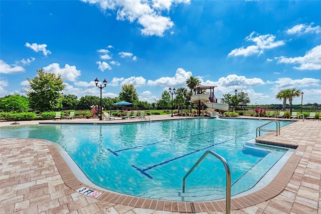 view of swimming pool featuring a water slide and a patio area