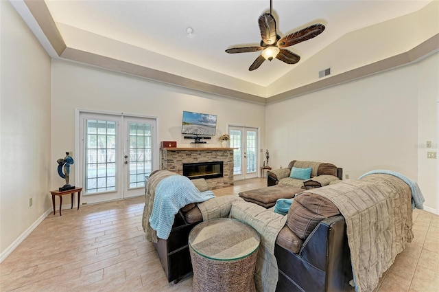 living room with a stone fireplace, vaulted ceiling, french doors, and ceiling fan