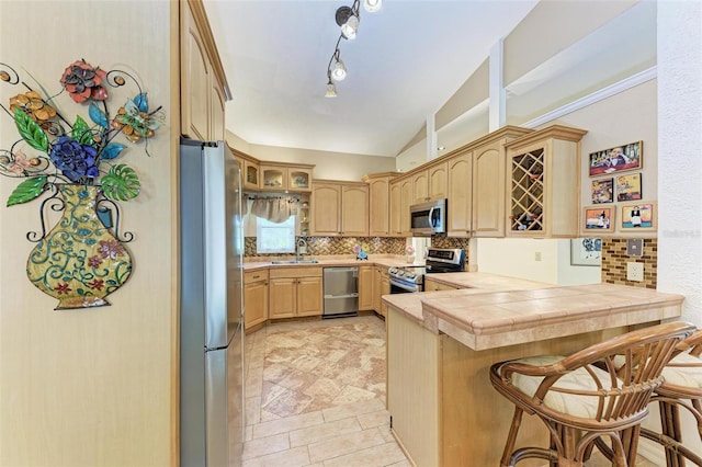 kitchen featuring a breakfast bar, backsplash, stainless steel appliances, tile countertops, and kitchen peninsula