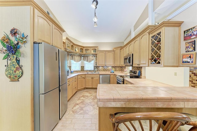 kitchen featuring a kitchen bar, backsplash, kitchen peninsula, and appliances with stainless steel finishes