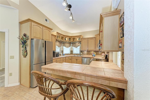 kitchen featuring sink, tile countertops, kitchen peninsula, stainless steel appliances, and backsplash