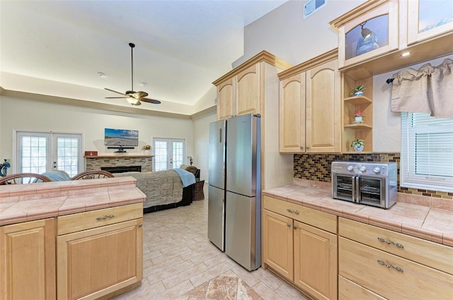 kitchen with stainless steel refrigerator, backsplash, light brown cabinetry, tile countertops, and french doors