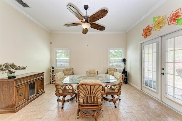 dining room with crown molding, a healthy amount of sunlight, and light wood-type flooring