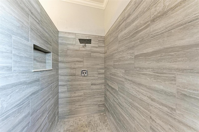 bathroom with ornamental molding and a tile shower