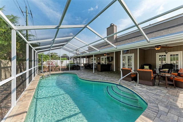 view of pool with a lanai, ceiling fan, a patio, an outdoor living space, and french doors