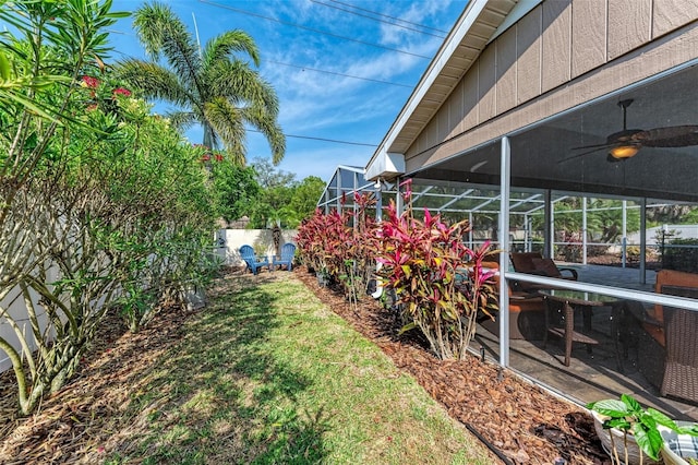 view of yard featuring ceiling fan and a lanai