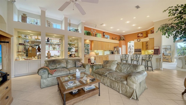 tiled living room with a high ceiling, ornamental molding, ceiling fan, and built in shelves