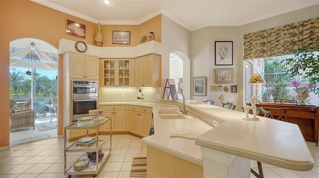 kitchen featuring a kitchen bar, sink, light brown cabinetry, and kitchen peninsula