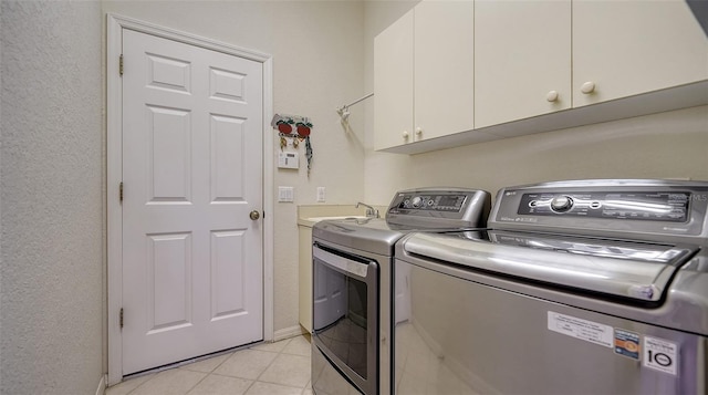 washroom featuring light tile patterned floors, sink, washing machine and dryer, and cabinets