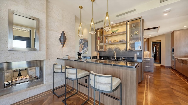 bar with dark parquet flooring, decorative light fixtures, sink, and backsplash