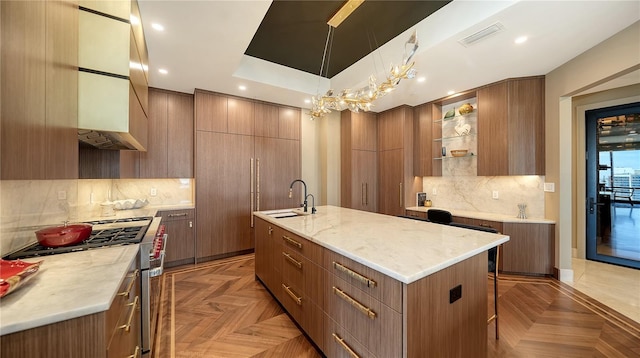 kitchen featuring parquet flooring, a kitchen island with sink, sink, and stainless steel range