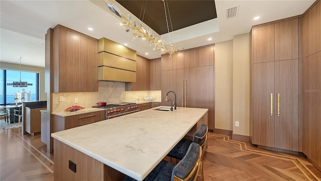 kitchen with double oven range, sink, and an island with sink