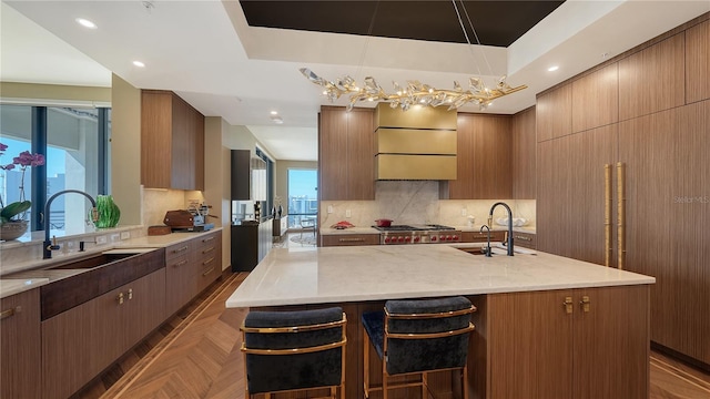 kitchen with an island with sink, sink, a breakfast bar, and decorative light fixtures