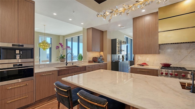 kitchen with pendant lighting, sink, a breakfast bar area, light parquet floors, and light stone countertops