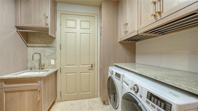 laundry room with sink, washer and clothes dryer, and cabinets