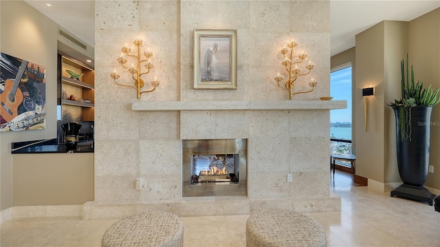 living room featuring a water view, a high end fireplace, and built in shelves