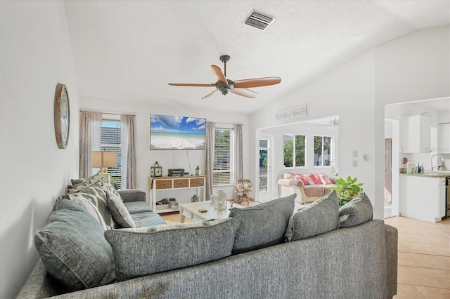 living room with lofted ceiling, a textured ceiling, ceiling fan, and light tile patterned flooring