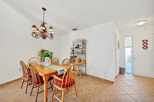 dining room featuring a chandelier, a textured ceiling, and light tile patterned floors