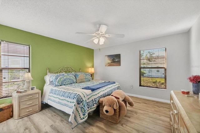 bedroom with ceiling fan, light hardwood / wood-style floors, and a textured ceiling