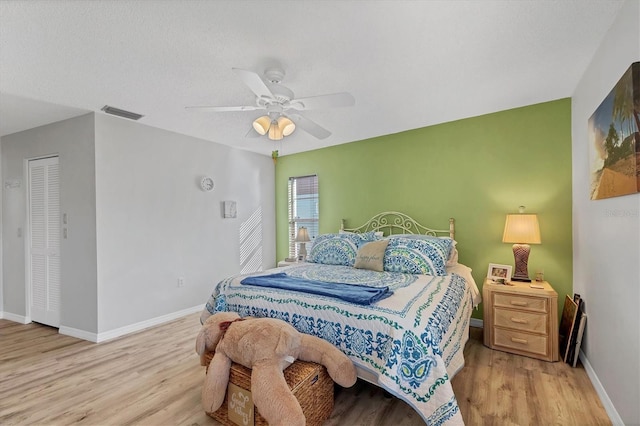 bedroom with a textured ceiling, ceiling fan, and light wood-type flooring