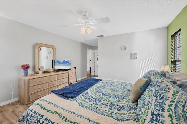 bedroom featuring ceiling fan, a textured ceiling, and light wood-type flooring