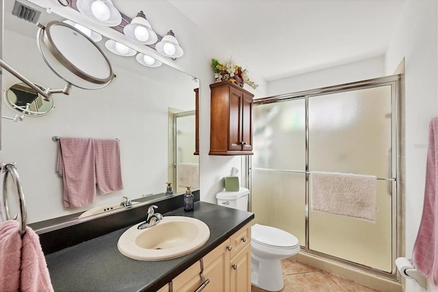 bathroom with toilet, vanity, a shower with door, and tile patterned flooring