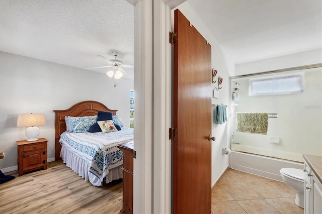 bedroom with ceiling fan, light tile patterned floors, multiple windows, and a textured ceiling