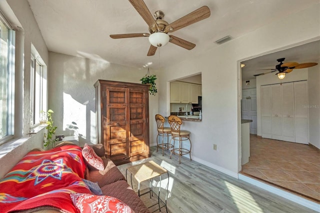 living room featuring sink, ceiling fan, and light hardwood / wood-style flooring