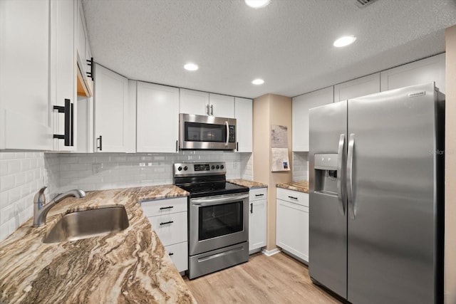 kitchen featuring light stone countertops, white cabinetry, appliances with stainless steel finishes, and sink