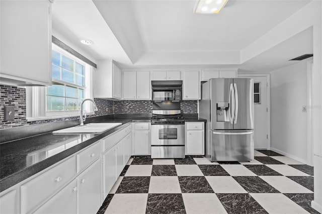 kitchen featuring tasteful backsplash, sink, white cabinets, a tray ceiling, and stainless steel appliances