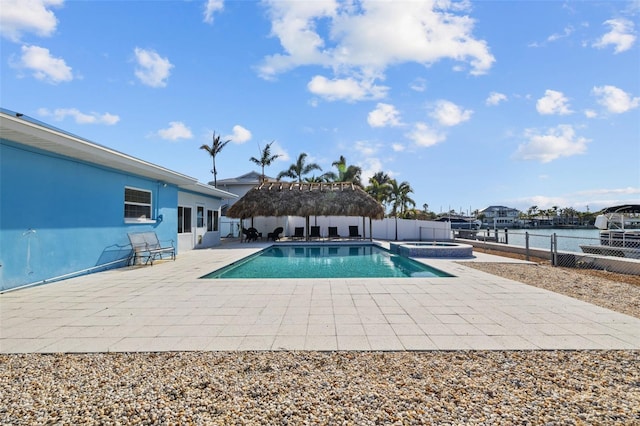 view of pool with a patio, a water view, and an in ground hot tub