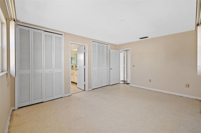 unfurnished bedroom with two closets and ensuite bathroom