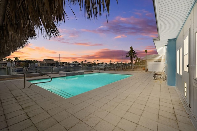 pool at dusk with a patio and an in ground hot tub