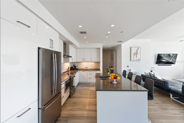 kitchen with appliances with stainless steel finishes, sink, white cabinets, decorative backsplash, and light hardwood / wood-style floors