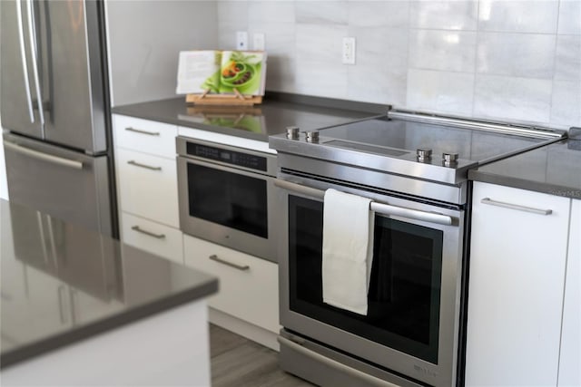 kitchen with stainless steel appliances, dark hardwood / wood-style floors, and white cabinets