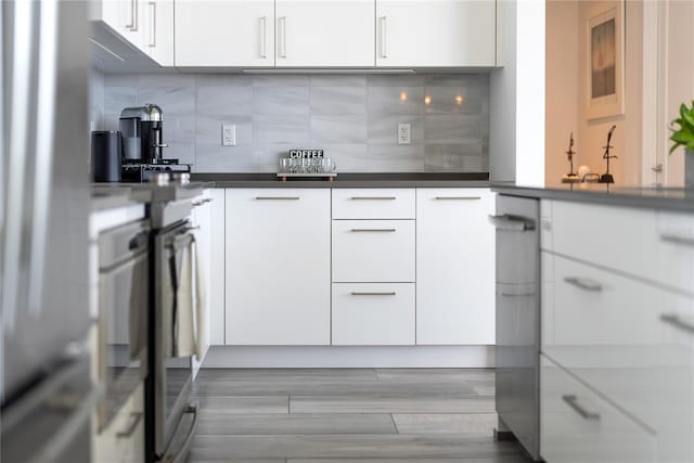 kitchen with sink, white cabinets, light wood-type flooring, and decorative backsplash