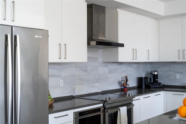 kitchen featuring white cabinetry, appliances with stainless steel finishes, backsplash, and wall chimney range hood