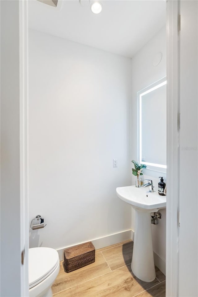 bathroom with hardwood / wood-style flooring and toilet