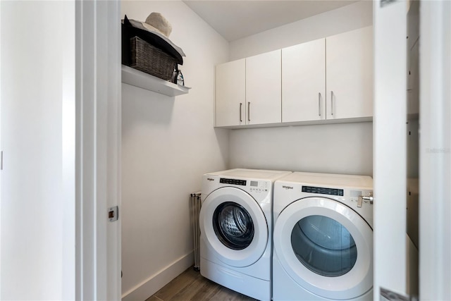 clothes washing area with dark wood-type flooring, cabinets, and washer and dryer