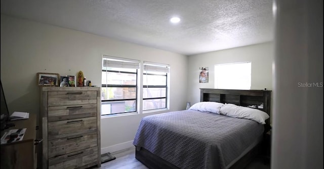 bedroom with light wood-type flooring and a textured ceiling