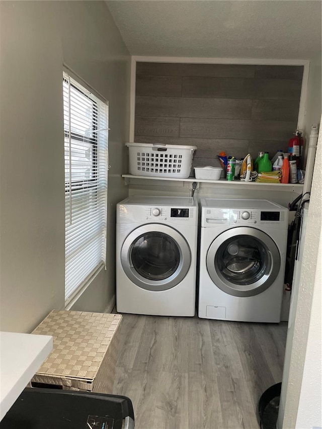 clothes washing area featuring separate washer and dryer, wood-type flooring, and wood walls