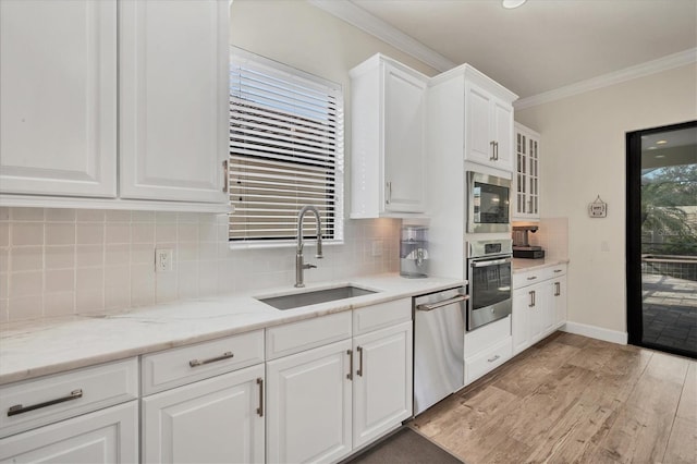 kitchen with sink, appliances with stainless steel finishes, ornamental molding, light hardwood / wood-style floors, and white cabinets