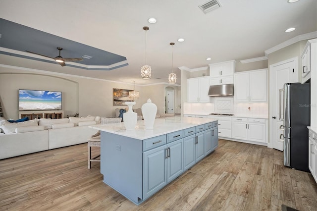 kitchen with white cabinetry, hanging light fixtures, stainless steel refrigerator, gas cooktop, and a kitchen island