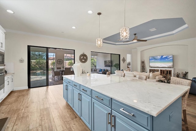 kitchen featuring decorative light fixtures, a breakfast bar area, ornamental molding, a center island, and blue cabinetry