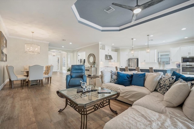 living room with crown molding, ceiling fan with notable chandelier, and light hardwood / wood-style floors