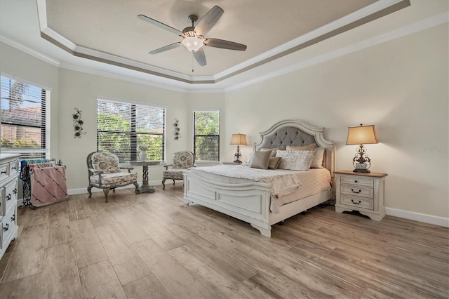 bedroom featuring a raised ceiling, crown molding, ceiling fan, and light wood-type flooring