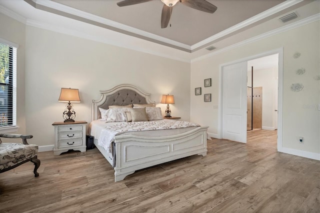 bedroom with ornamental molding, a raised ceiling, and hardwood / wood-style floors