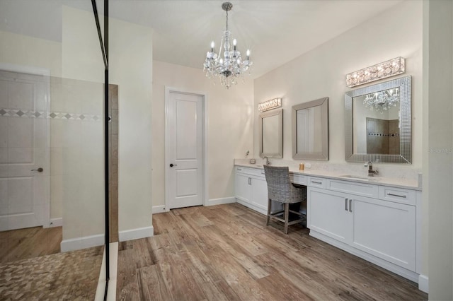 bathroom with vanity, wood-type flooring, a chandelier, and a tile shower